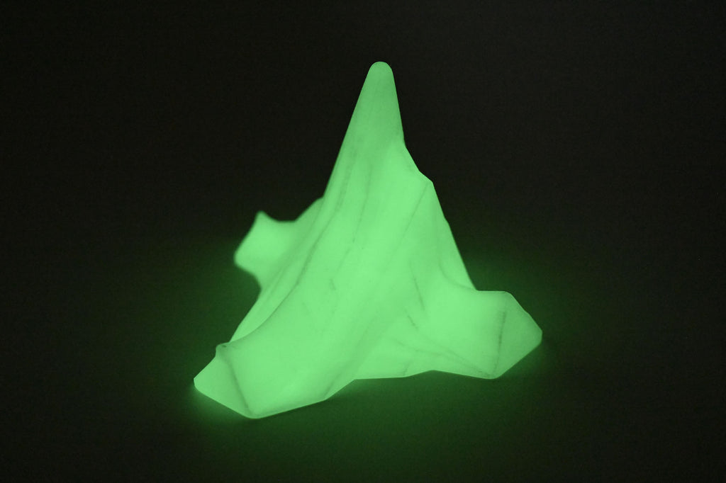 Glow-in-the-dark Titanic iceberg model glowing bright green in a dark room